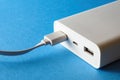 White power bank and cable in usb port on blue background Royalty Free Stock Photo