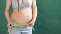 Pregnant woman measuring stomach with measuring tape