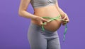 Pregnant woman measuring stomach with measuring tape