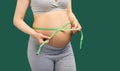 Pregnant woman measuring stomach with measuring tape