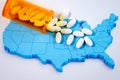 White pharmaceutical pills spilling from prescription bottle over map of America Royalty Free Stock Photo