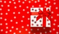 White present box with red ribbon and bow on red background with decorative snowflakes. Christmas gift concept. Festive and Royalty Free Stock Photo