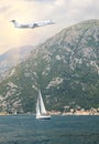 White private jet business jet flies against backdrop of beautiful spectacular views of boat in middle of bay with mountain