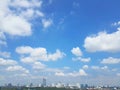 White puffy cumulus clouds over cityscape with blue skies