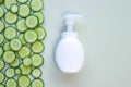 White pump cream bottle and fresh cucumber slices on light green background. Liquid soap or cleansing cream bottle. Cosmetic Royalty Free Stock Photo