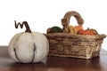 White pumpkin on wooden table with assortment of pumpkins on basket on the background