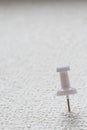 A white push pin is pinned on a white surface. Royalty Free Stock Photo
