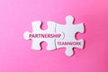White puzzle pieces with words PARTNERSHIP and TEAMWORK on background, top view