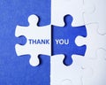 White puzzle with separated piece and phrase THANK YOU on background, top view