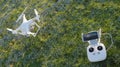 White quadcopter drone with remote controller over a green grass