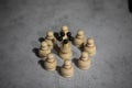 white queen wooden chess piece surrounded by white pawns standing on gray table Royalty Free Stock Photo