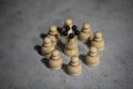 white queen wooden chess piece surrounded by white pawns standing on gray table Royalty Free Stock Photo
