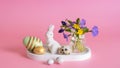 White rabbit, flowers and Easter eggs on a pink background. Easter still life composition.