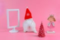 White rabbit with red christmas hat and chrismas tree and white picture frame, copy space for text. Royalty Free Stock Photo