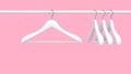 White rack with white clothes hangers isolated on pink background