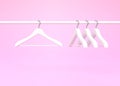 White rack with white clothes hangers isolated on pink background