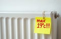 White radiator has yellow sticky note with red text max 19c. attached. Reminder for temperature setting to save energy during Royalty Free Stock Photo