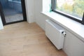 White radiator heating with thermostat for energy saving in unfinished home room repair with balcony door