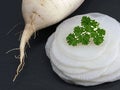 white radish thinly sliced on black slate board garnished with parsley, close up of fresh healthy root vegetable Royalty Free Stock Photo