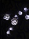 White rattan balls light garland. New Year`s garland. Christmas led lights on dark background. Blurred glowing light bulb garland Royalty Free Stock Photo