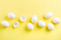 White raw chicken eggs lying in horizontal row with broken egg on yellow background. Royalty Free Stock Photo