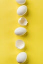 White raw chicken eggs lying in vertical row with broken egg on yellow background. Top view Royalty Free Stock Photo