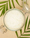 White rice grain in a glass bowl and palm leaves