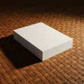 A white rectangular box with straight edges sits on a brown woven mat, casting a Royalty Free Stock Photo