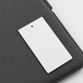A white rectangular card with a small hole near one end is placed on a textured dark Royalty Free Stock Photo
