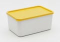 A white rectangular container with a yellow lid placed on a flat surface Royalty Free Stock Photo