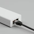 White rectangular electronic device connected to a black Ethernet cable. The cable is Royalty Free Stock Photo
