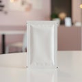A white, rectangular, foil packet stands vertically on a glossy, white tabletop. The packe Royalty Free Stock Photo