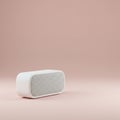 White, rectangular portable speaker with rounded edges on an even, muted pink background