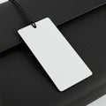 A white rectangular tag is attached to a black textured surface, likely a piece of luggag Royalty Free Stock Photo