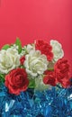 White and red artificial flowers on a red background with blue tinsel. Selective focus Royalty Free Stock Photo