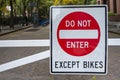 White red black street sign reading do not enter except bikes