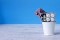 White, red, black and yellow tablets in the plates are in a decorative bucket, white and blue background. Medicine, health concept