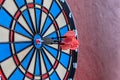 White, red and blue dartboard hanging on a wall. Dartboard with three darts in the center