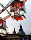 White and red clear glass gondola and detail of giant Ferris wheel in Budapest with church tower in the background Royalty Free Stock Photo