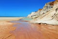 White and red cliffs near the sea at Morro Branco, Ceara, Brasil. At the base clear water stream and blue clear sky at the horizon Royalty Free Stock Photo