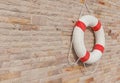 The white and red life buoy is hanging on the brick wall around Royalty Free Stock Photo