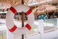 White red lifebuoy hang under tropical palm leaf umbrella, blurry white blue lifebuoy at background Royalty Free Stock Photo