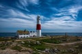 White and red lighthouse on the shore near the sea under the breathtaking sky Royalty Free Stock Photo