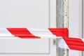 A white and red plastic caution tape on a metal rod against a light background