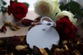 White and red roses, dried petals with blank tag label paper for your notes on a gift of a book on messy table.  Still life. Royalty Free Stock Photo