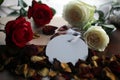 White and red roses, dried petals with blank tag label paper for your notes on a gift of a book on messy table.  Still life Royalty Free Stock Photo