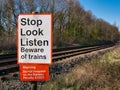 White and red signs warn those crossing the railway to look and listen for trains and that it is an offense to trespass.