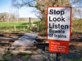 White and red signs warns those crossing the railway to look and listen for trains and that it is an offense to trespass.