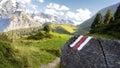 White and red trail waymark in a hiking path in the Swiss Alps with blurred background Royalty Free Stock Photo