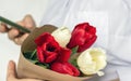 white red tulips flowers bouquet in brown paper in woman hand arm white shirt Royalty Free Stock Photo